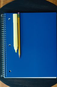 Blocco note chiuso con copertina blu, matita ed evidenziatore