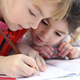 Due bambine stanno disegnando su un quaderno di scuola